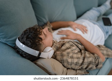 one teenager man young caucasian male use headphones for online guided meditation practice mindfulness yoga with eyes closed at home real people self care manifestation concept copy space generation Z - Shutterstock ID 2364878151