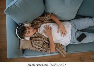 one teenager man young caucasian male use headphones for online guided meditation practice mindfulness yoga with eyes closed at home real people self care manifestation concept copy space generation Z - Shutterstock ID 2364878157