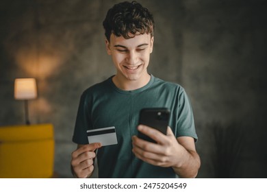 One teenager young man caucasian male sit at home use credit card and laptop computer shopping online use internet for online purchase active modern e-banking hold mobile phone and credit card - Powered by Shutterstock