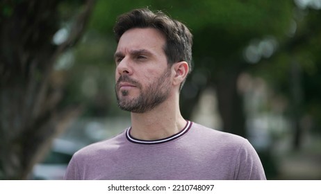 One Thoughtful Young Man Walking Outdoors In City Street. Pensive Male 30s Person Walks With Serious Expression