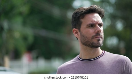 One Thoughtful Young Man Walking Outdoors In City Street. Pensive Male 30s Person Walks With Serious Expression