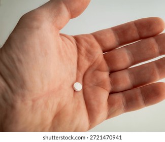 One Tiny Round White Pill Resting on Open Palm