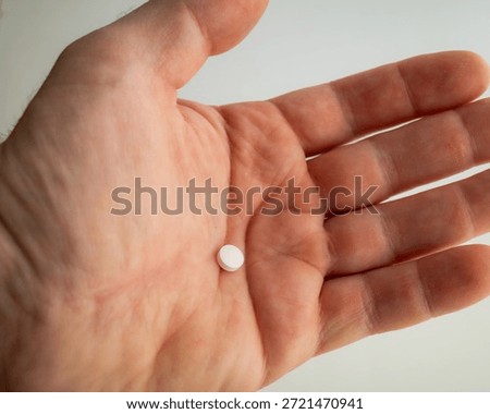 One Tiny Round White Pill Resting on Open Palm