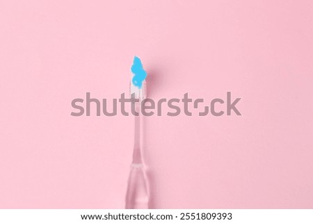 One toothbrush with toothpaste on pink background