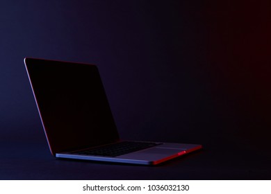 One Turned Off Laptop With Reflecting Screen On Dark