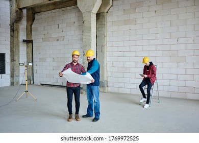 One of two engineers pointing at sketch on blueprint and specifying details while consulting with colleague on background of man with tablet