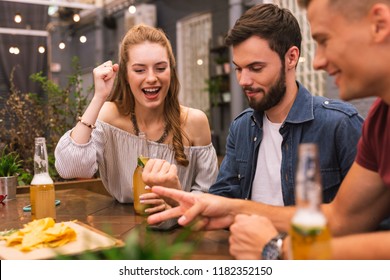Uno, dos, tres. Jóvenes amigos sentados en el bar y sonriendo mientras juegan papel de tijeras de rock