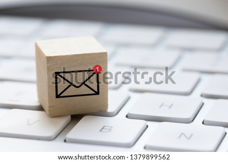 One unread e-mail message concept with computer keyboard and e-mail symbol on wooden cube
