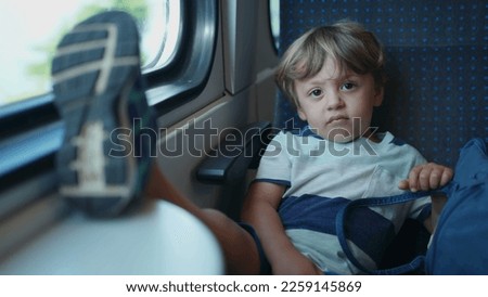 One upset child with feet on table while traveling by train. Mischievous small kid not behaving on moving transportation
