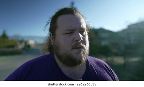 One upset young overweight man walks outside closeup face. Tracking shot of a male fat person with concerned angry expression - Powered by Shutterstock