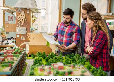 One of urban architects showing sketch on blueprint to his colleagues while discussing it - Powered by Shutterstock