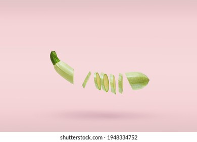 One vegetable marrow fresh sliced many small slices flying on pink background. Concept levitation food. Copy space for text.
