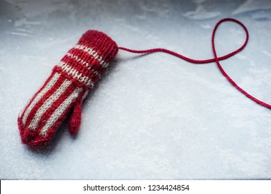 One Vintage Red And White Woolen Mitten On A Frozen Surface