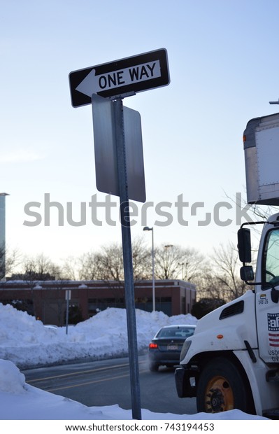 one way signal sign road street direction to\
a certain place or location during the winter weather holidays with\
the front of a white truck 