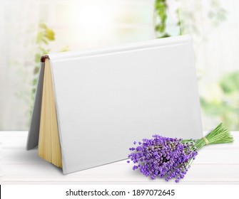 One White Book, Standing Upright On A White Wooden Desk With Flowers