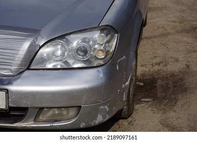 One White Front Glass Headlight On A Gray Passenger Car On The Street