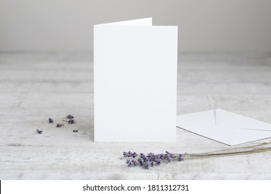 One white greeting card mockup, standing upright on a white wooden desk. Blank, closed card template with envelope.  - Shutterstock ID 1811312731