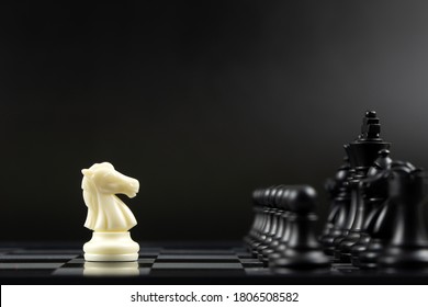 One white knight chess piece facing all black chess pieces for fierce competition situation, one against many concept