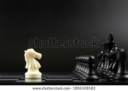 One white knight chess piece facing all black chess pieces for fierce competition situation, one against many concept