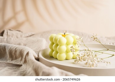 One White Square Bubble Candle On A Concrete Tray On A Linen Table Cloth With A Blooming Branch