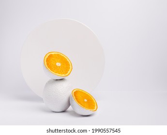 One Whole Orange And Two Halves Of Oranges Leaning On Each Other Painted In White. Creative Food Concept. Abstract And Unique Fruit.