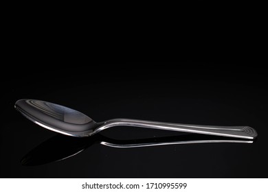 One Whole Steel Silver Spoon Isolated On Black Glass