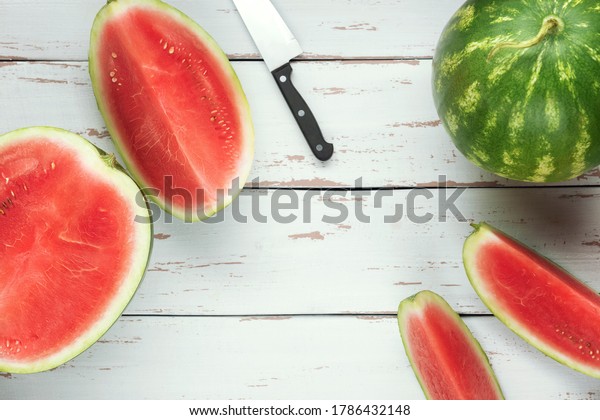 One whole\
watermelon with pieces of sliced one and knife on the white wooden\
Provence style background. Flat\
lay.