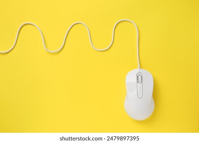 One wired mouse on yellow background, top view. Space for text