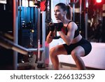 One woman doing goblet squat exercise in a gym with a dumbbell