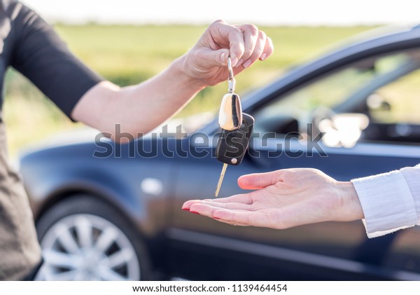 One woman hands over another car key. Rent or\
purchase of auto - concept.