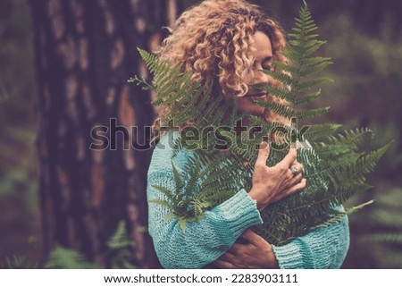 One woman hugging big tropical leaves. Nature lover and environment lifestyle. People feeilng and connection with nature. Happiness life. Forest green woods ambient protection concept image. Balance