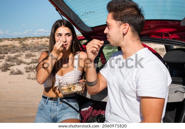 One\
woman and one man eating and chatting in a car while travelling at\
Bardenas Reales desert, Navarra, Basque\
Country.