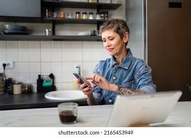 One woman mature caucasian female using mobile phone in the kitchen in the morning daily routine real people leisure and relaxation concept copy space making a call talking happy smile - Powered by Shutterstock