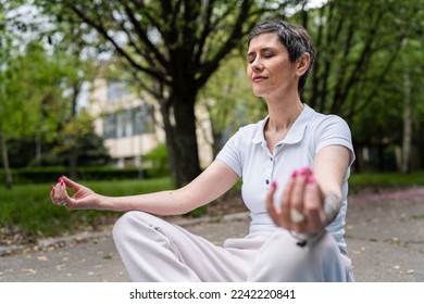 one woman mature caucasian senior female sit outdoor on yoga mat meditate front view real people meditation self-care manifestation practice mental emotional balance concept eyes closed - Powered by Shutterstock