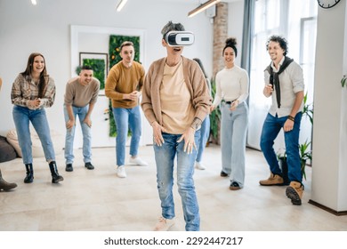 One woman mature senior caucasian female in front of group of men and women friends enjoy virtual reality VR headset at work having fun together during team building seminar real people bright filter - Powered by Shutterstock