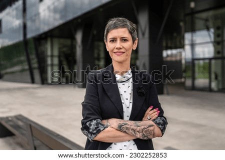 One woman mature senior caucasian female stand outdoor arms crossed confident in front of modern building in city real people copy space front view waist up tattoo on hand