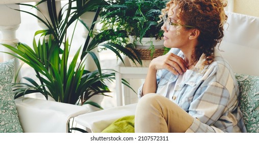 One woman sitting at home in the garden with green plants around and looking. Thoughtful female people single lifestyle concept. Adult lady thinking and enjoying relax. Beautiful hipster woman - Powered by Shutterstock