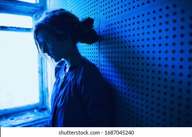 One Woman Standing Worry Upset Near Night Window Lit Low Key Light. Dark Hair Adult Lady Head, Stress Side Face Alone Young Teen Girl Tired. Fear Grief, Mental Pain, Lonely Mind, Phobia Guilt Concept.