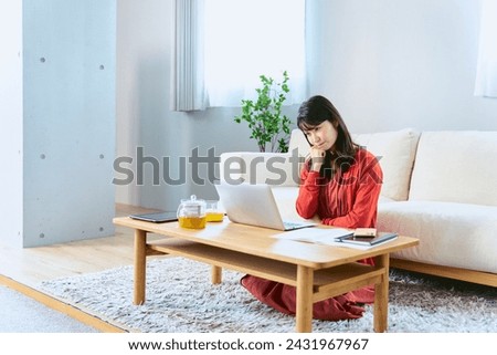 One woman taking an online course at a low table in the living room of a designer apartment living alone