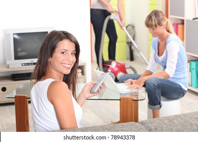 One Woman Watching Tv, A Woman Doing Computer And Someone Vacuuming