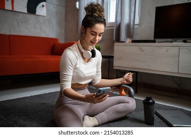 One Woman Young Adult Caucasian Female Sporty Holding Mobile Phone Using Internet For Online Training At Home Real People Sport Health And Fitness Concept Copy Space