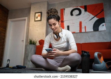 One Woman Young Adult Caucasian Female Sporty Holding Mobile Phone Using Internet For Online Training At Home Real People Sport Health And Fitness Concept Copy Space