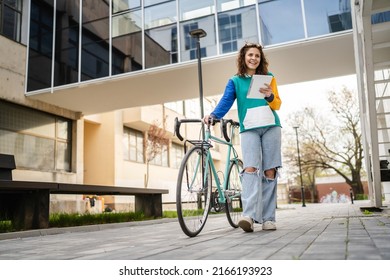 One Woman Young Adult Caucasian Female Walking By The University Building Holding Bicycle And Digital Tablet In Day Real People Copy Space Happy Joyful Full Length Front View