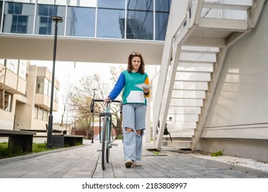 One Woman Young Adult Caucasian Female Walking By The University Building Holding Bicycle And Digital Tablet In Day Real People Copy Space Happy Joyful Full Length Front View