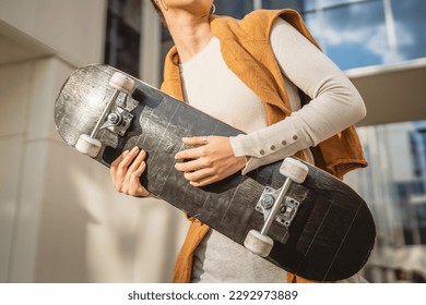 One woman young adult caucasian female stand outdoor posing portrait happy confident hold skateboard in front of modern building in sunny day copy space - Powered by Shutterstock