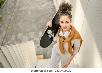 One woman young adult caucasian teenager stand outdoor with skateboard on her shoulder posing portrait happy confident real person copy space - Powered by Shutterstock