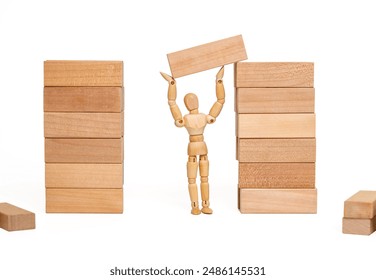 One wooden figurine builds a house out of blocks. Concept about construction and repair. Connect blocks in sequence. - Powered by Shutterstock