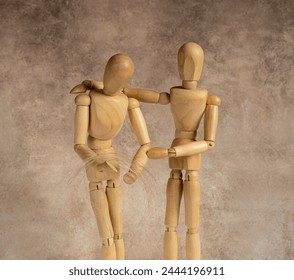 one wooden mannequin helping another as friend in need - Powered by Shutterstock