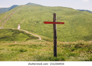 One Wooden Red Signpost In The Summer Mountain With Copyspace. Conceptual Leading Indicator. Old Arrow On The Wooden Signpost Pointing To A Direction.