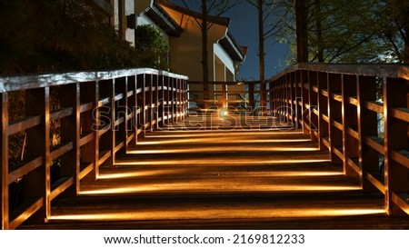 One wooden walk way with the lights on at night